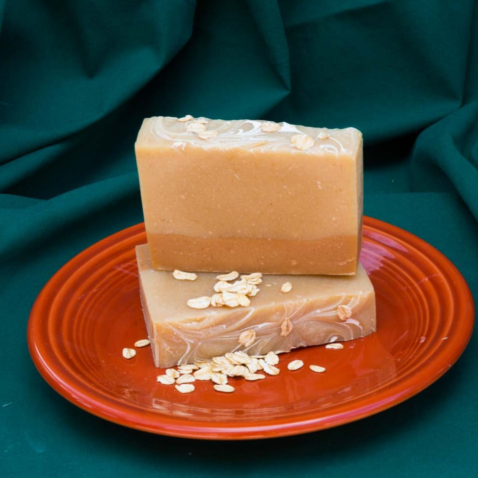 2 bars of oatmeal soap on a plate with oats